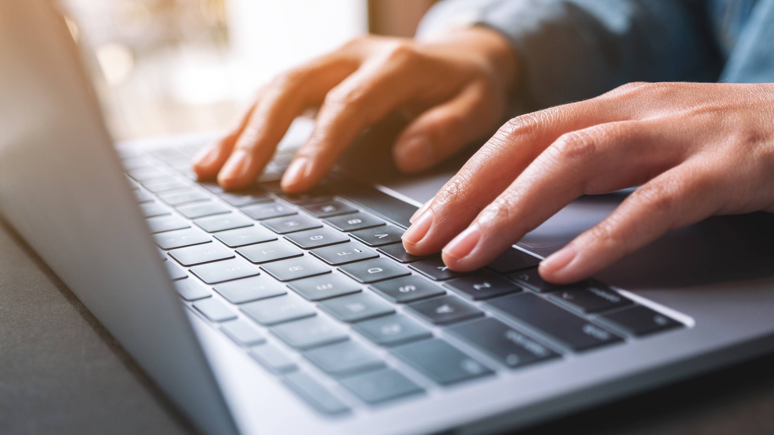 Closeup of a woman working and typing on laptop computer on the table