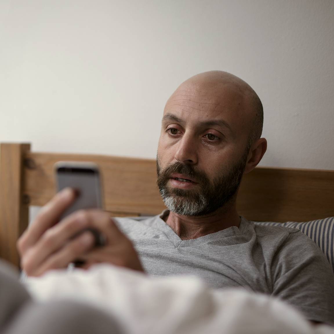 man in bed using phone